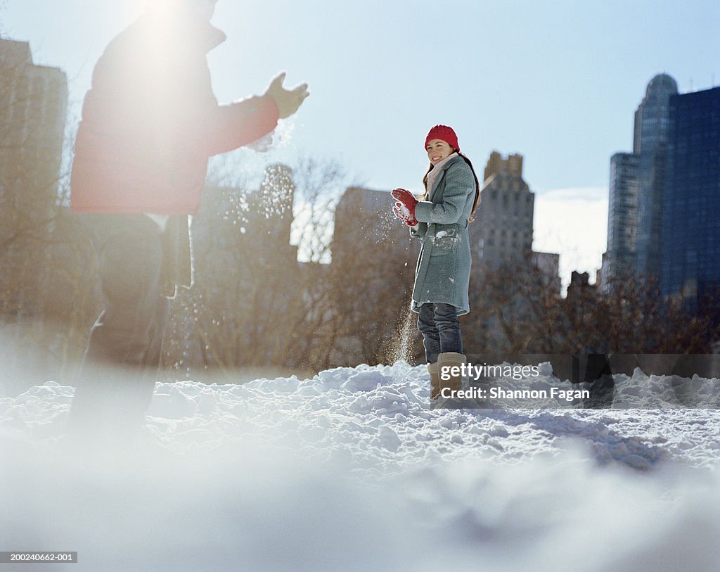 Young couple having snowball fight in park, winter, low angle view