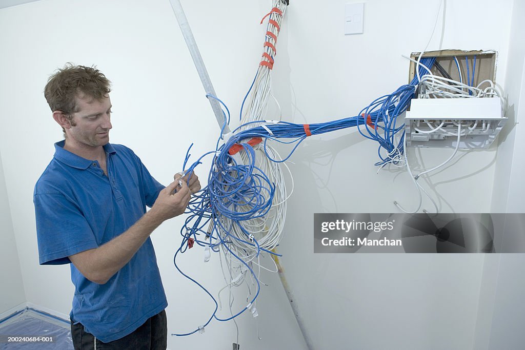 Young electrician marking up cables in junction box