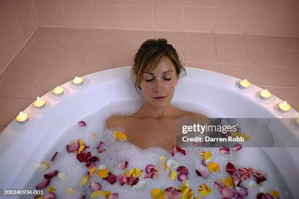 young woman lying in bath with rose petals and candles, elevated view - beautiful woman bath stockfoto's en -beelden