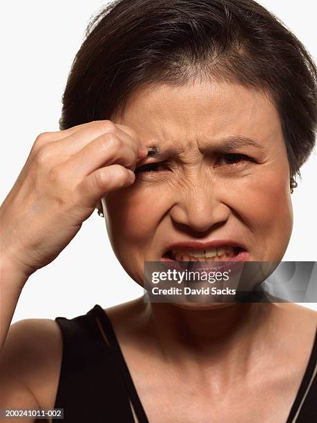 mature woman tweezing eyebrow, grimacing, portrait, close-up - tweezing eyebrows stock pictures, royalty-free photos & images