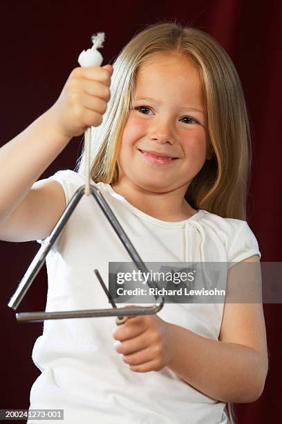 girl (4-6) playing triangle, smiling, close-up - triangle percussion instrument stock pictures, royalty-free photos & images