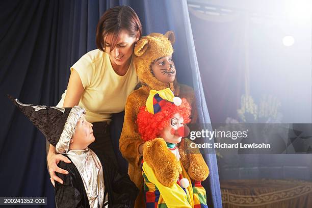 children (4-8) behind stage curtain, teacher talking to boy in wizard costume - bear suit 個照片及圖片檔