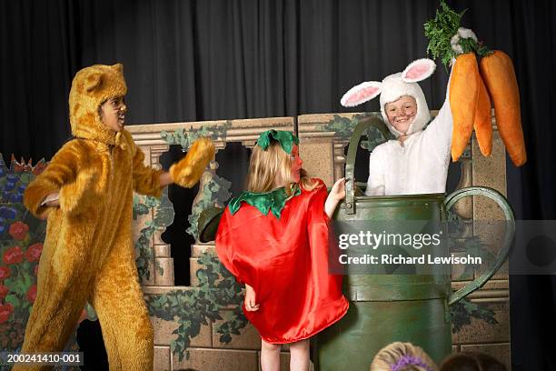 three children (5-9) in food and animal costumes performing on stage - children theater stock-fotos und bilder