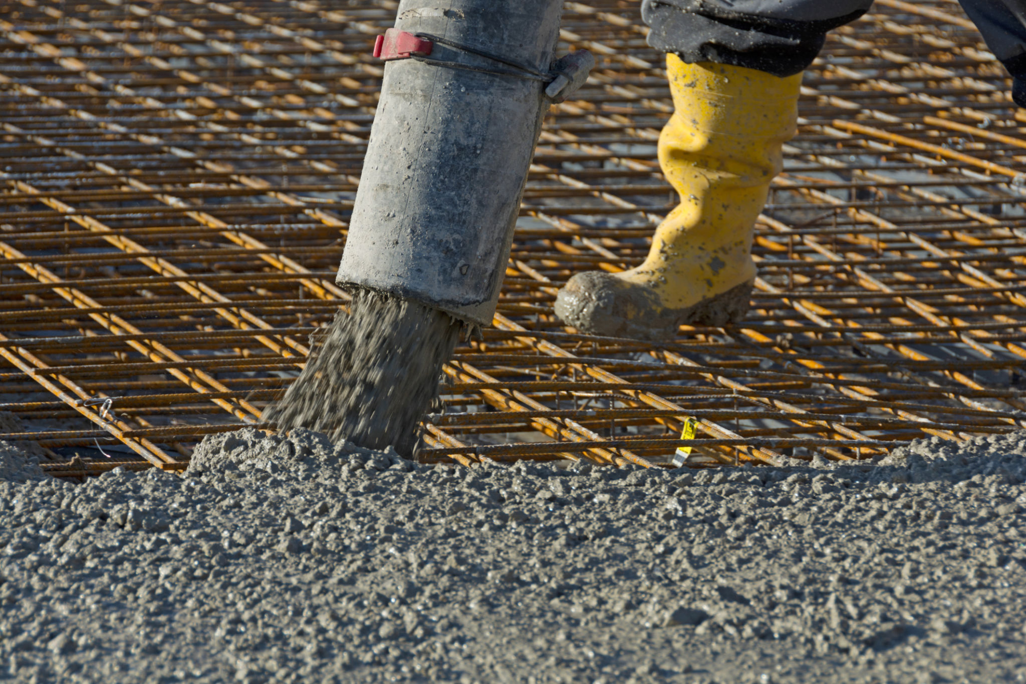 Construction worker pours concrete on rebar using concrete pump Construction worker pours concrete on rebar using concrete pump
