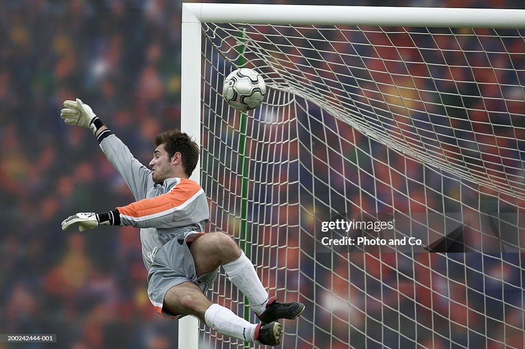 Male football goalie trying to block goal in air
