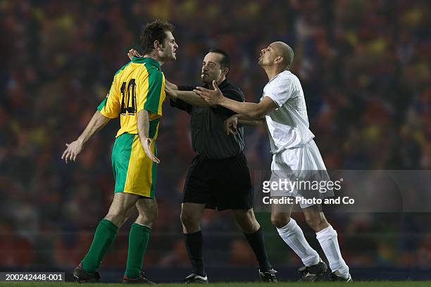 referee breaking up dispute between two male football players - face off sports play stock pictures, royalty-free photos & images