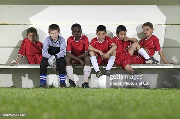 football team of boys (8-12) sitting on bench, portrait - side lines imagens e fotografias de stock