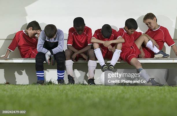 football team of boys (8-12) sitting on bench, looking down - vanquish stock pictures, royalty-free photos & images