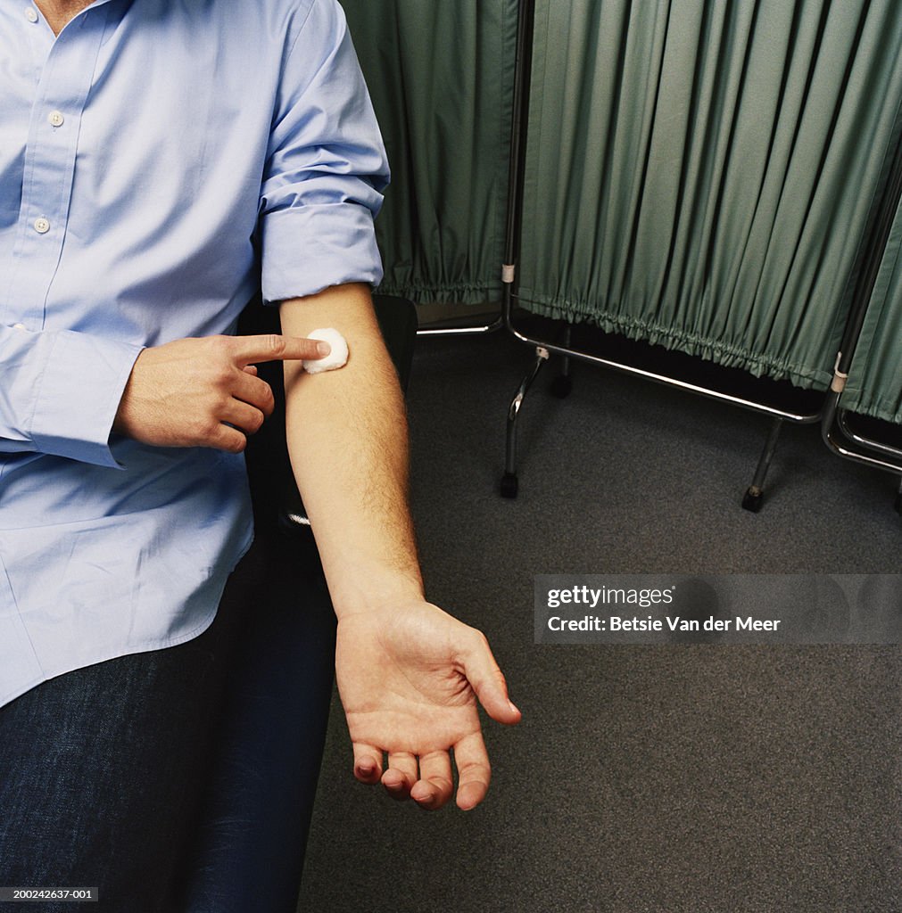 Young man holding cotton ball on arm