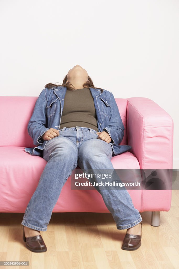 Young woman sitting on a couch with her head leaning over