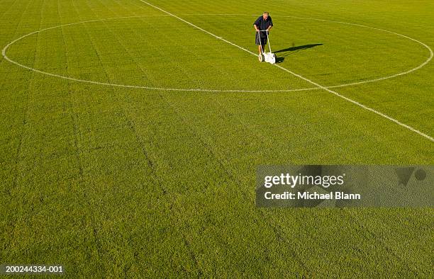 mature groundsman marking lines on football pitch, elevated view - idrottsplatspersonal bildbanksfoton och bilder