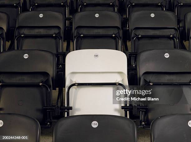 single white seat amongst black seats in empty stadium, close-up - empty stadium stock-fotos und bilder