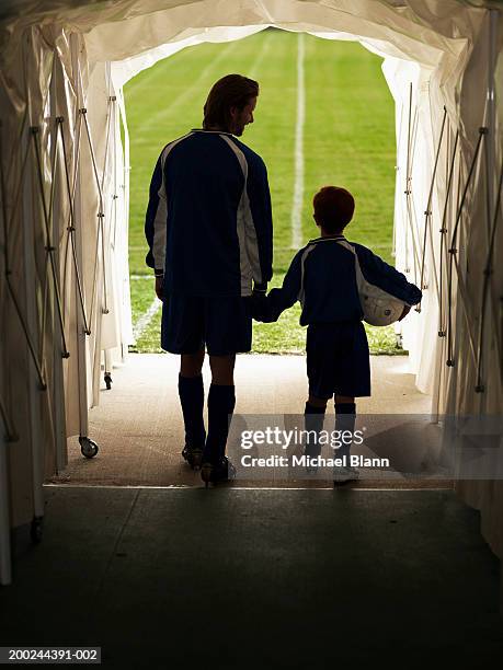 footballer and mascot (8-10) in tunnel leading to pitch, rear view - football pitch bildbanksfoton och bilder