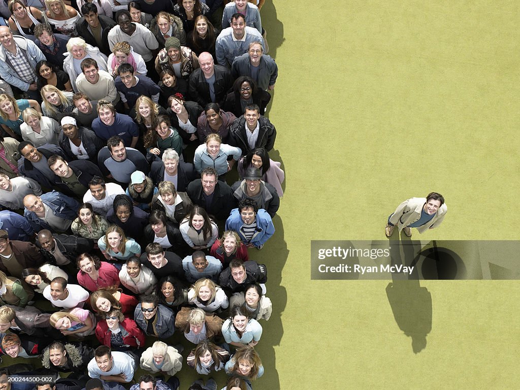 Young man standing to side of large crowd looking up, overhead view