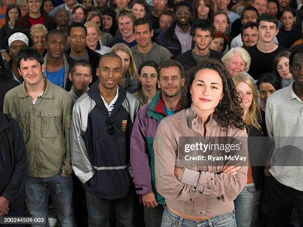young woman standing in front of crowd, arms folded, portrait - abundance stock pictures, royalty-free photos & images