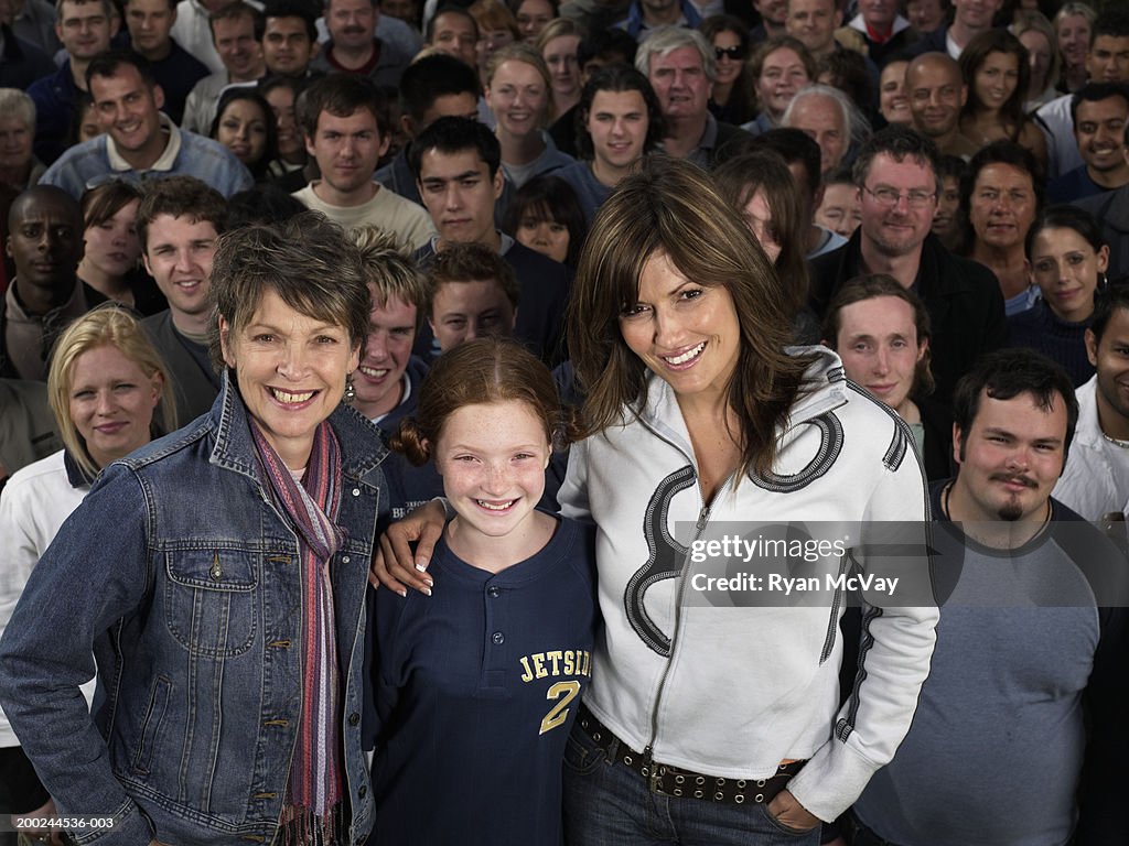 Three generational women in front of crowd, smiling, portrait