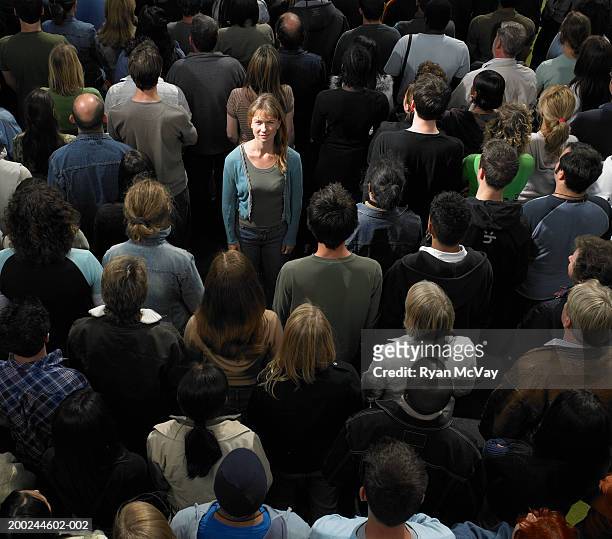 one woman facing opposite direction to crowd, looking up, portrait - standing out from the crowd stock pictures, royalty-free photos & images