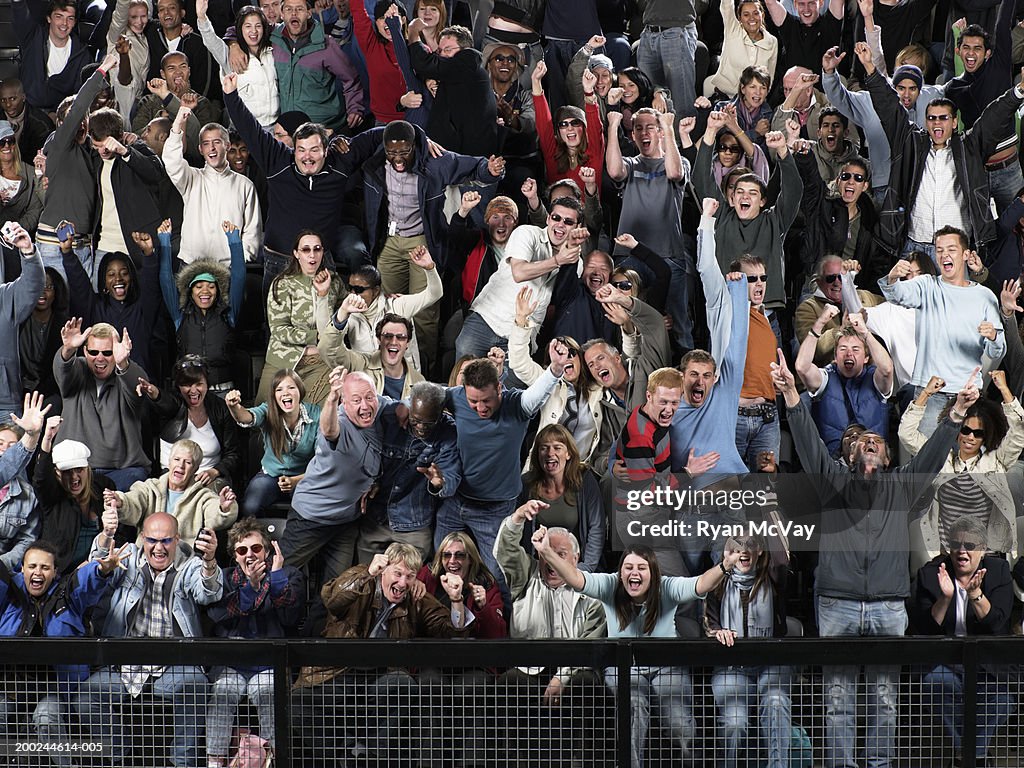 Stadium crowd celebrating, embracing and waving arms, full frame