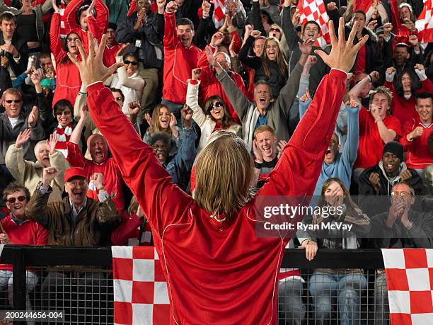 footballer raising arms in front of cheering crowd, rear view - waving-sports-flag stock pictures, royalty-free photos & images