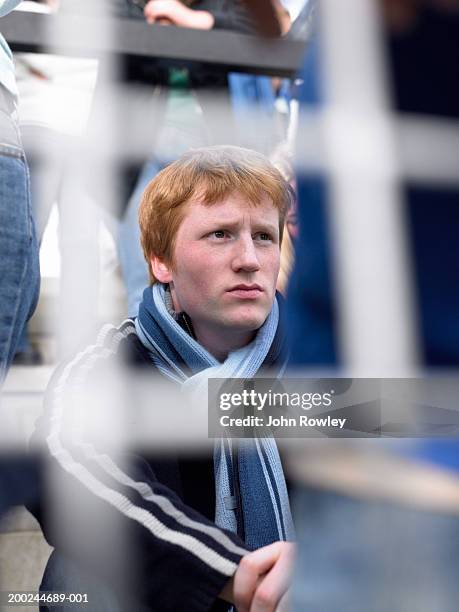 male football fan sitting behind goal, frowning, view through net - boy tracksuit stock pictures, royalty-free photos & images