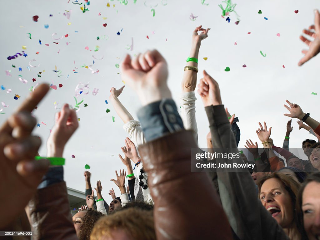 Confetti falling over cheering stadium crowd, low angle view