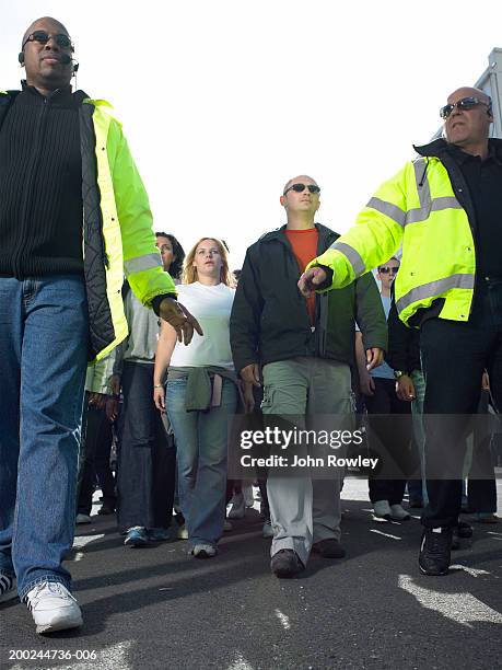 two security guards standing with backs to crowd, low angle view - ir detrás fotografías e imágenes de stock