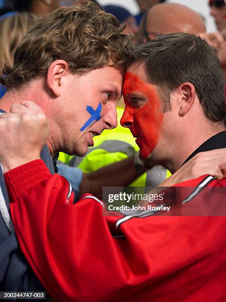two rival fans standing head to head in stadium crowd, close-up - confrontación fotografías e imágenes de stock