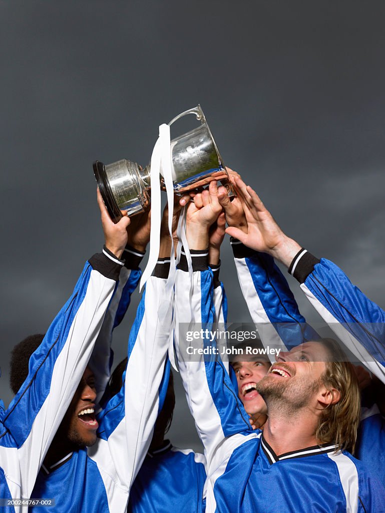 Footballer players raising trophy cup, low angle view