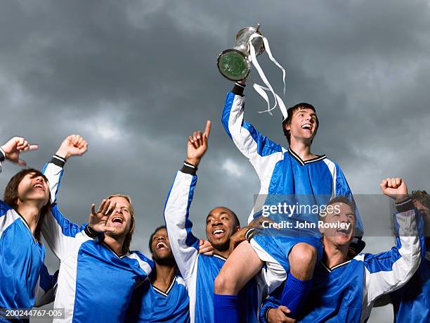 footballer players celebrating, one raised by others, waving trophy - premios el club de las 25 fotografías e imágenes de stock