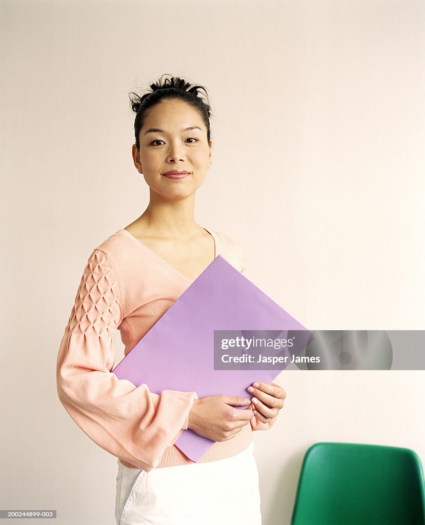Woman holding file, smiling, portrait