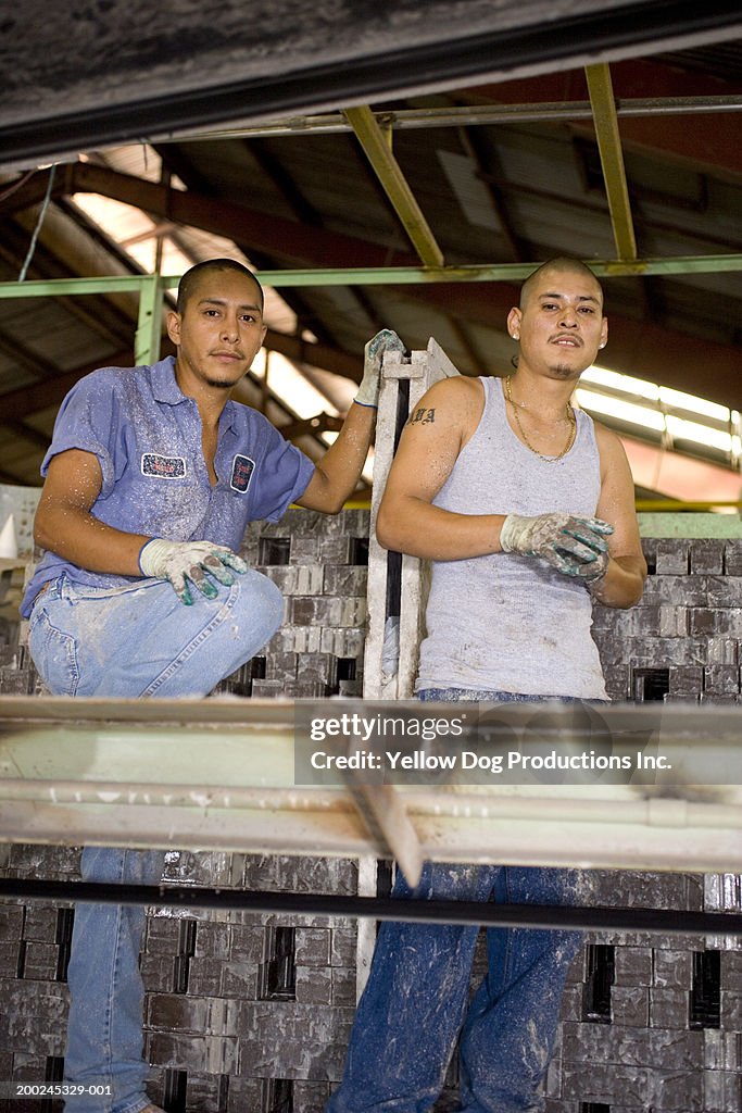 Two male construction workers in factory, portrait, low angle view