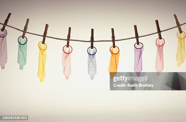 condoms hanging on pegs from line - condoom stockfoto's en -beelden