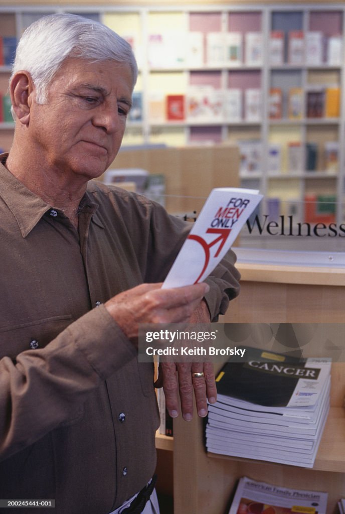 Man in chemist looking at prostate brochure