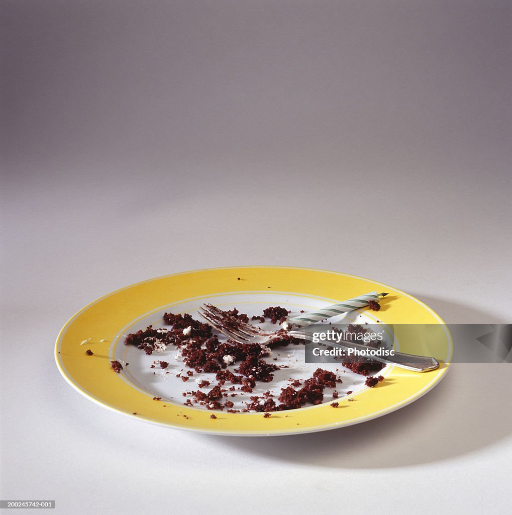 Empty plate with crumbs and candle, elevated view