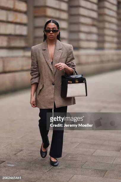 Cherifa Akili seen wearing YSL black sunglasses, gold earrings, Yes My Love beige / black houndstooth pattern elegant blazer jacket, Khaite black...
