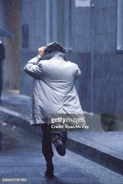 man running in rain, rear view - trench coat back stock pictures, royalty-free photos & images