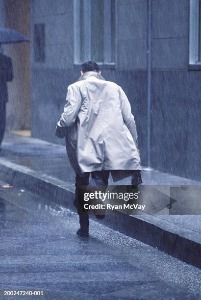 man running in rain, rear view - trench coat back stock pictures, royalty-free photos & images