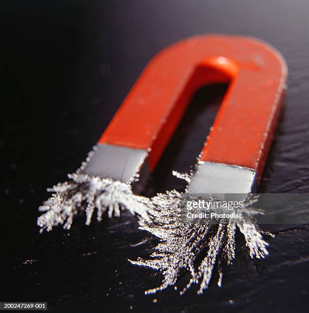 magnet attracting iron filings, elevated view - hoefijzermagneet stockfoto's en -beelden
