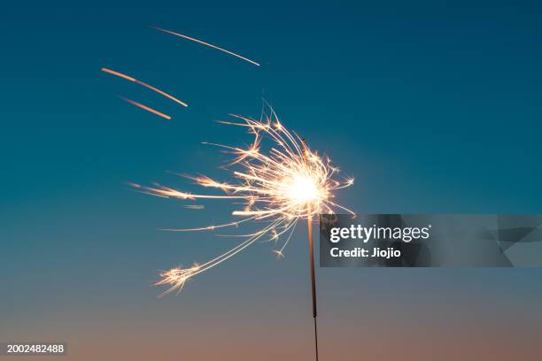 burning sparkler against sky - candela magica foto e immagini stock