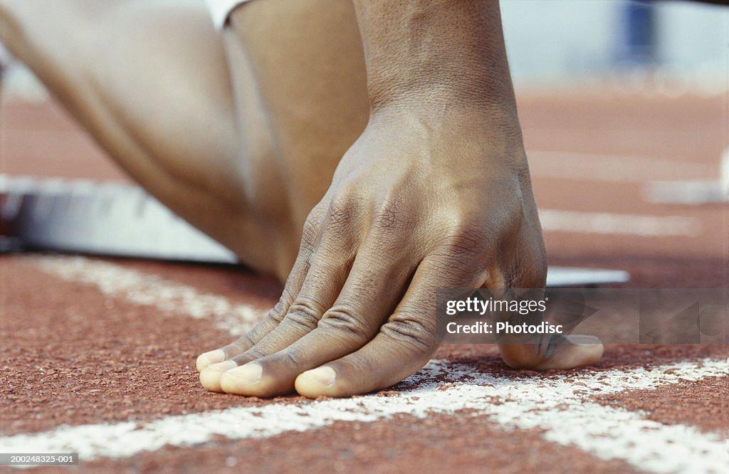 Person kneeling with hands on starting line, Close-up of hand