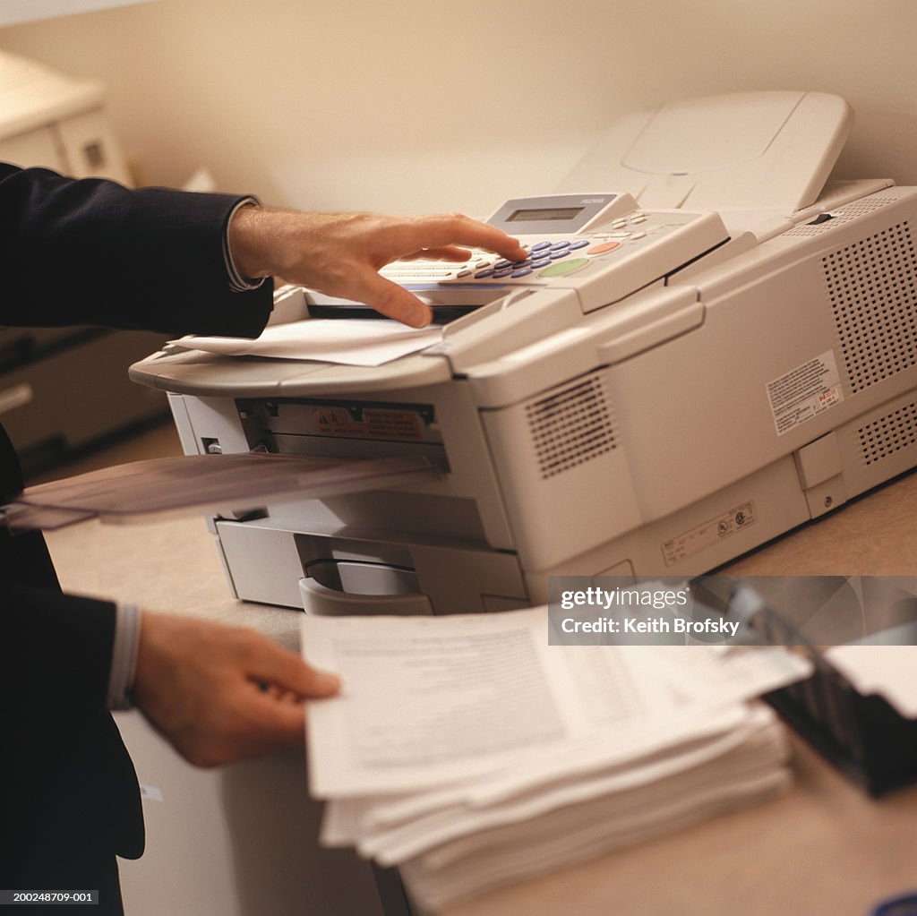 Businessman using fax machine, Close-up of hands