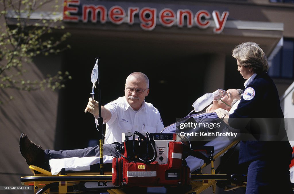 Paramedics taking patient on gurney into emergency ward at hospital