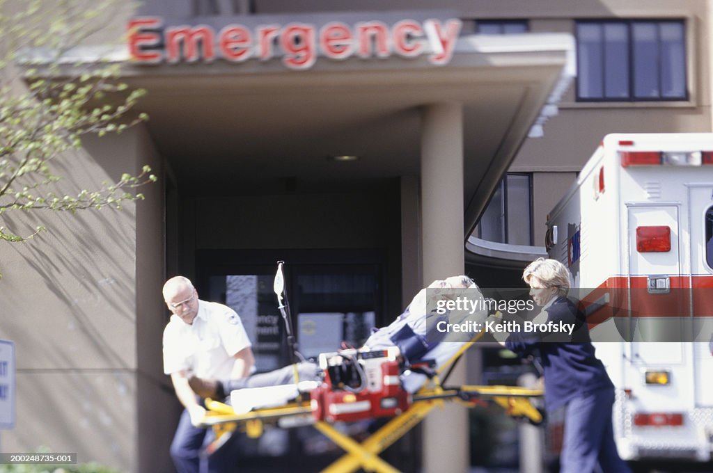Paramedics taking patient on gurney into emergency ward at hospital