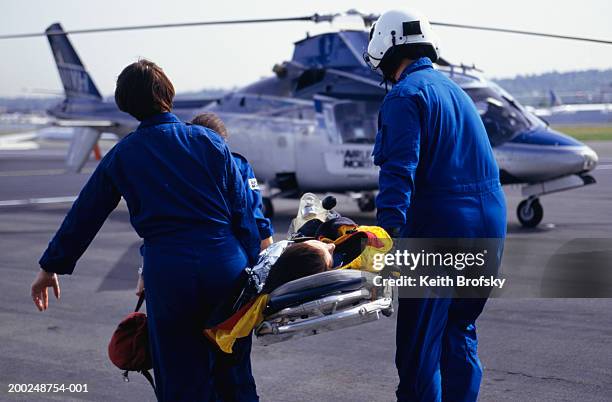 nurses and pilot carrying patient on stretcher to helicopter - elicottero-ambulanza foto e immagini stock