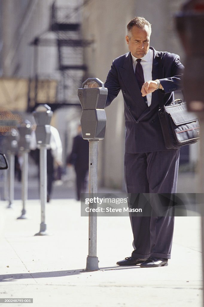 Businessman checking time at parking meter