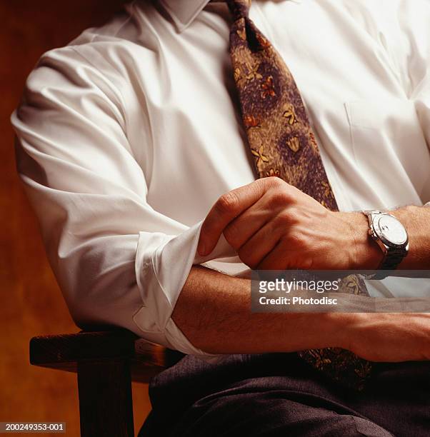 man rolling up sleeves, (close-up) - luxury watch stock-fotos und bilder