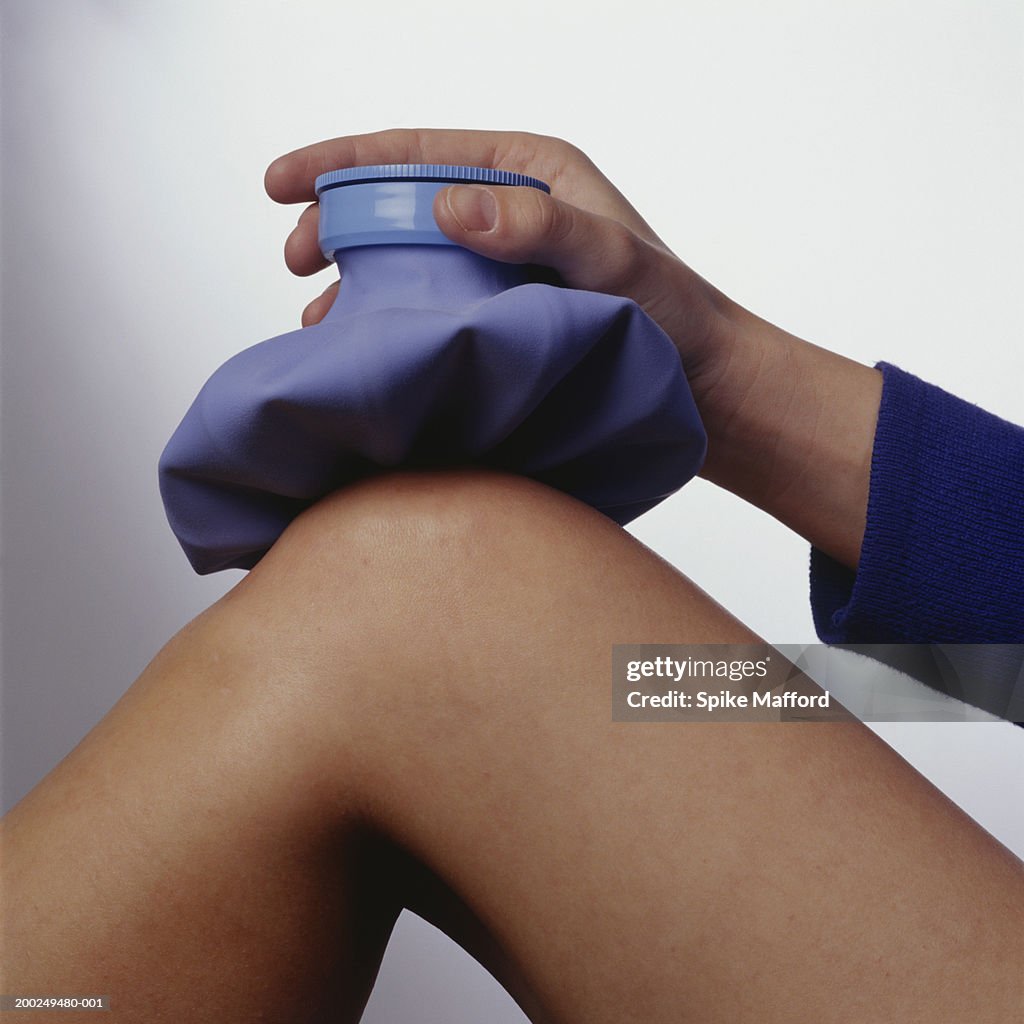 Woman applying ice pack to knee, (Close-up)