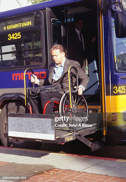 man in wheelchair exiting bus - wheelchair accessibility stock pictures, royalty-free photos & images