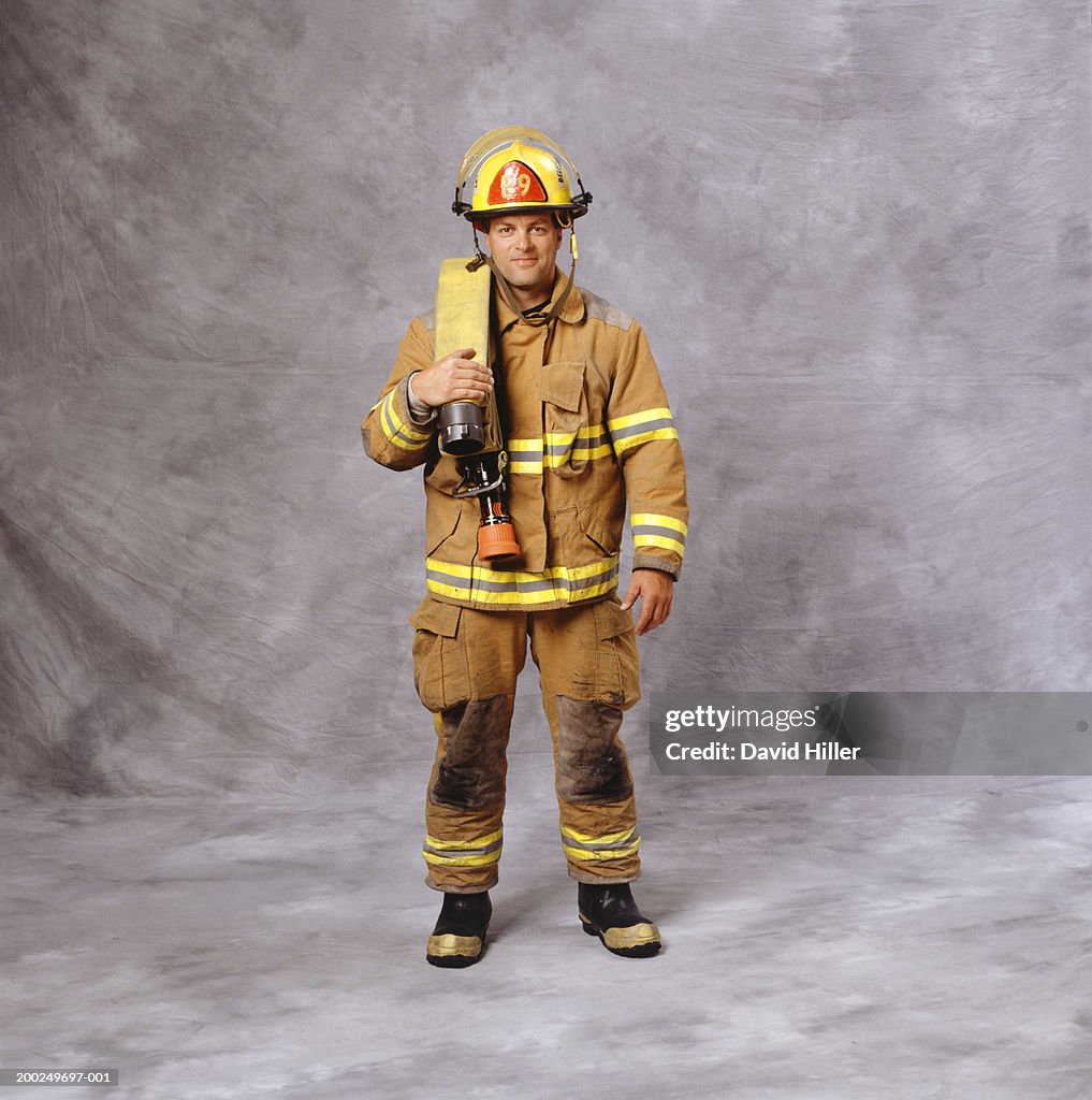 Fire-fighter with fire hose over shoulder, (Portrait)