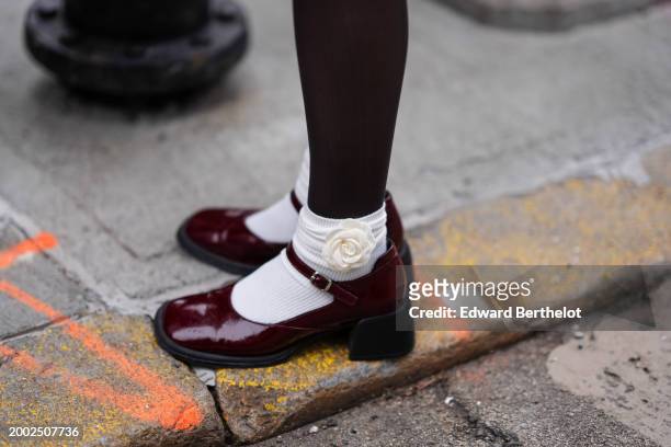 Close-up detail view of tights, white ribbed socks with floral detail, burgundy leather shoes, outside Eckhaus Latta, during New York Fashion Week,...